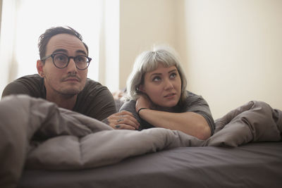 Young couple lying on bed watching tv