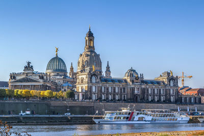 Boats in canal by buildings against sky in city