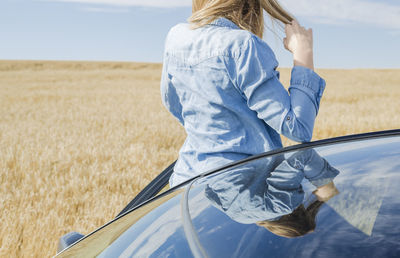 Rear view of mid adult woman disembarking from car against landscape