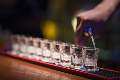 Midsection of person holding drink in glass on table