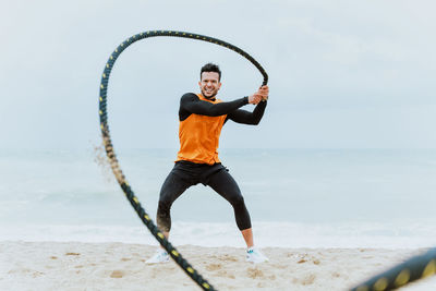 Dedicated man doing exercise with rope at beach
