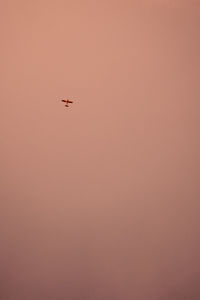 Low angle view of silhouette airplane against clear sky during sunset