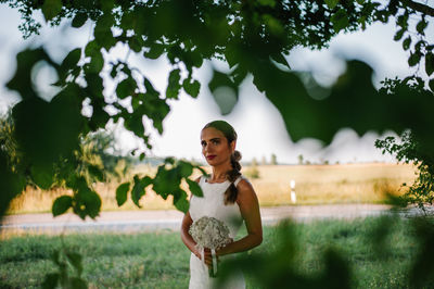 Portrait of woman standing against trees