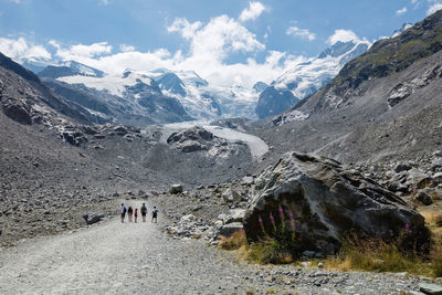 Hikers walking on dirt road passing through mountains