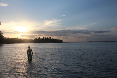 Silhouette man on beach against sky during sunset