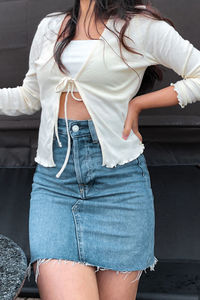 Midsection of woman standing against white wall