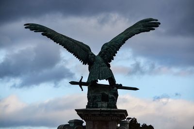 Low angle view of angel statue against cloudy sky