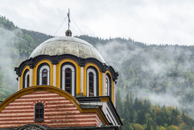 Dome of rila monastery in front of foggy mountains in bulgaria.