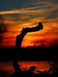 Silhouette man with arms outstretched against sky during sunset