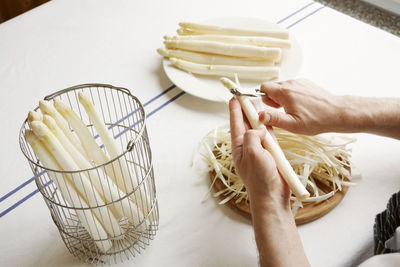 Cropped hand peeling asparagus on table at home