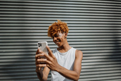 Young dark-skinned man posing at the street and taking selfie in the city background