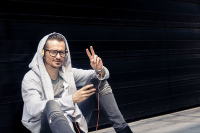 Full length portrait of young man sitting outdoors