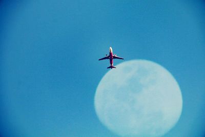 Low angle view of airplane flying against clear blue sky