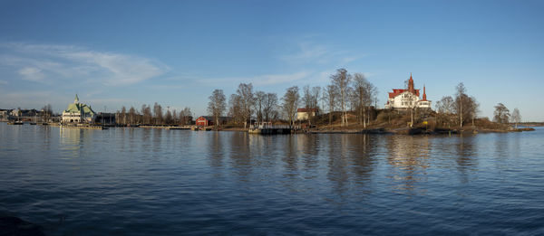 A panoramic view of an island with old wooden cottages in the middle of a city center during sunset.