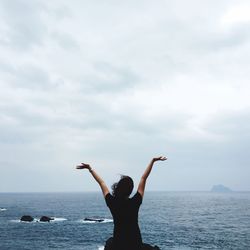 Woman standing in sea against sky