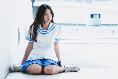 Full length thoughtful young woman kneeling on floor