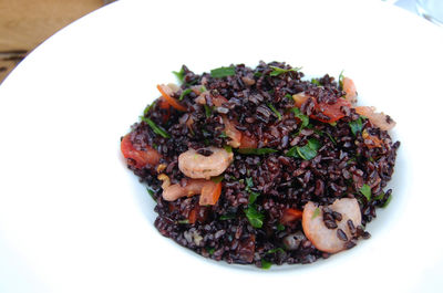 Close-up of black rice with prawns in plate