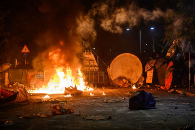 People standing by bonfire against fire at night