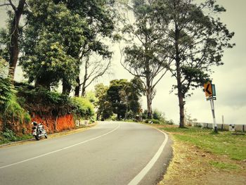 Empty road with trees in background
