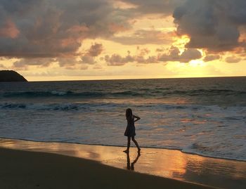 Man on beach against sky during sunset