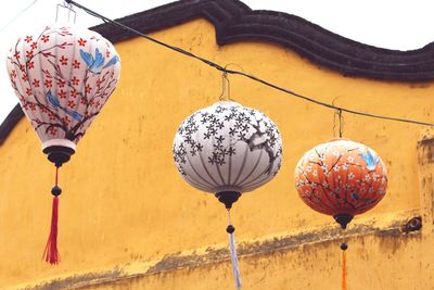 Low angle view of lanterns hanging on cable by building