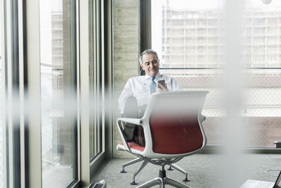 Senior manager in office sitting on chair talking on the phone