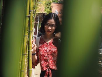 Woman looking down while standing against plants