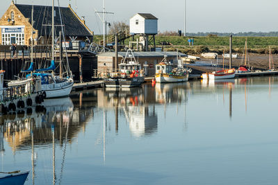 Boats moored at harbor against sky