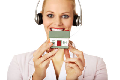 Portrait of smiling woman holding mobile phone against white background