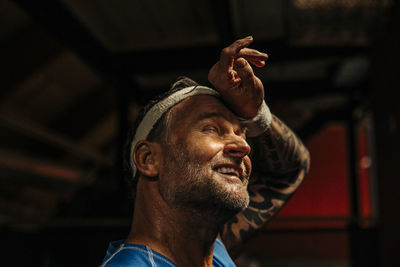 Tired male athlete wiping sweat from forehead at sports court