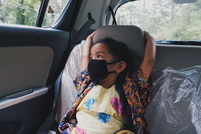 Young girl looking outside whilst sitting in a car