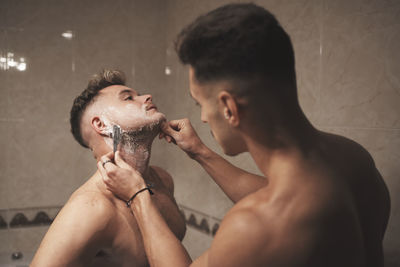 Midsection of shirtless man in bathroom