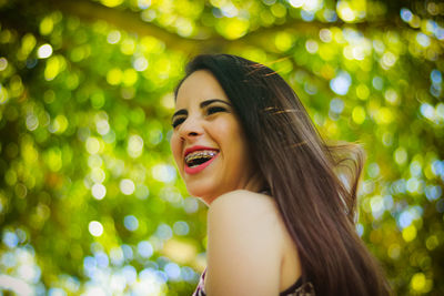 Close-up of happy young woman against tree