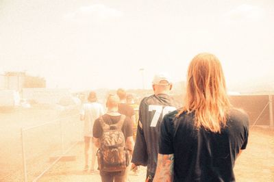 Rear view of people standing against clear sky