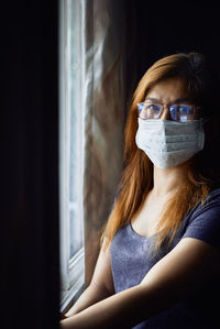 Woman in mask at the window during covid-19 pandemic