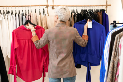 Young woman choosing clothes at store rear view