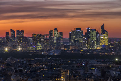 Illuminated cityscape against sky during sunset