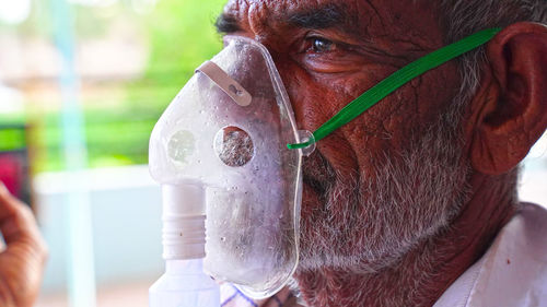 A elder person infected with covid 19 disease. patient inhaling oxygen wearing mask with liquid 