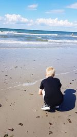 Rear view of boy sitting on beach