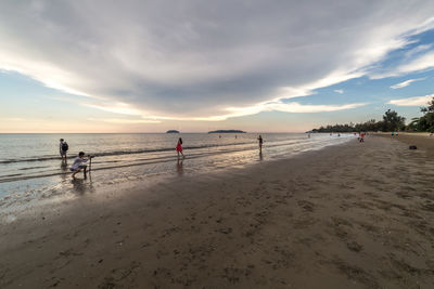 People on beach against sky during sunset