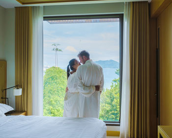 Couple men and women waking up in a hotel room looking out over the ocean