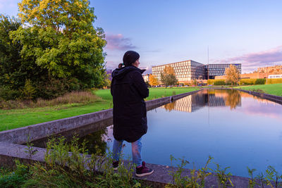 Woman in warm clothes stands in a park on the edge of a water channel. copenhagen, denmark