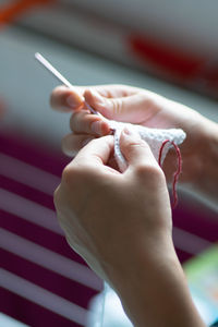 Cropped hands of woman crocheting at home