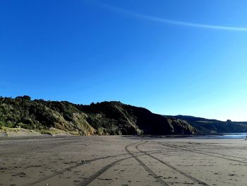 Surface level of road against clear blue sky