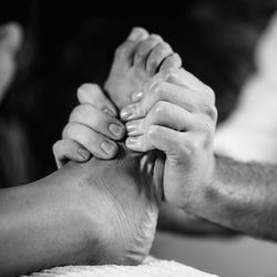 Cropped hands giving toe massage to customer