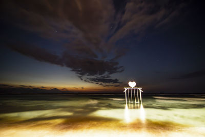 Illuminated light painting on land against sky at sunset