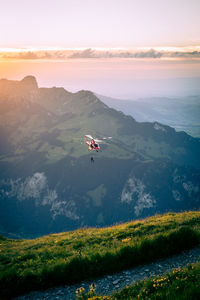 Helicopter flying over landscape against sky