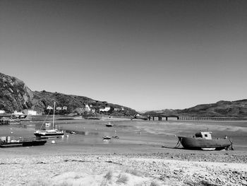 Boats moored on beach against clear sky