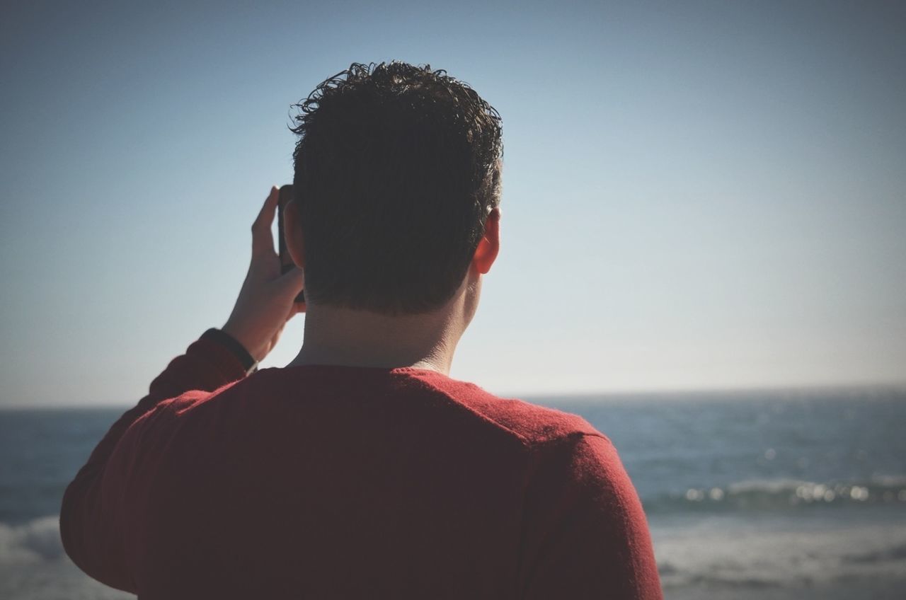 lifestyles, leisure activity, clear sky, rear view, beach, focus on foreground, headshot, casual clothing, waist up, person, young adult, standing, sea, copy space, men, head and shoulders, three quarter length, side view