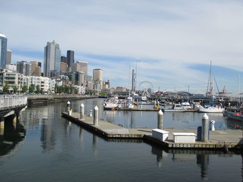 Boats moored at harbor against sky in city